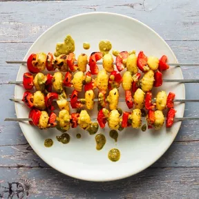 Foto van vegan bbq spiezen met gnocchi en paprika op een bord met pesto-dressing