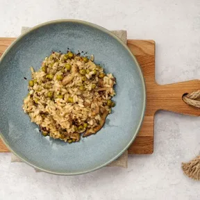 Foto van een bord met risotto met champignons en doperwten