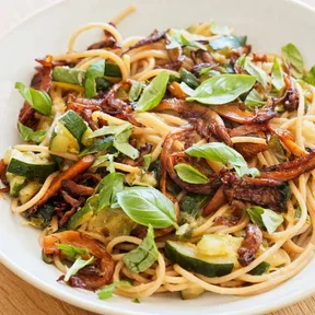 Foto van plantaardige spaghetti met saus van courgette en oesterzwammen bacon